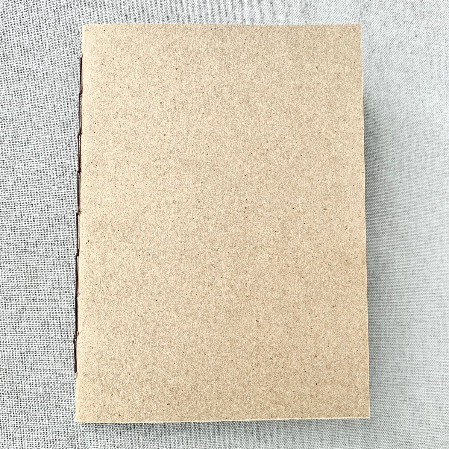 A hand-stitched travelers notebook insert with a kraft cover, designed as an A5 blank refill that is fountain pen friendly and ideal for journaling or planning.
