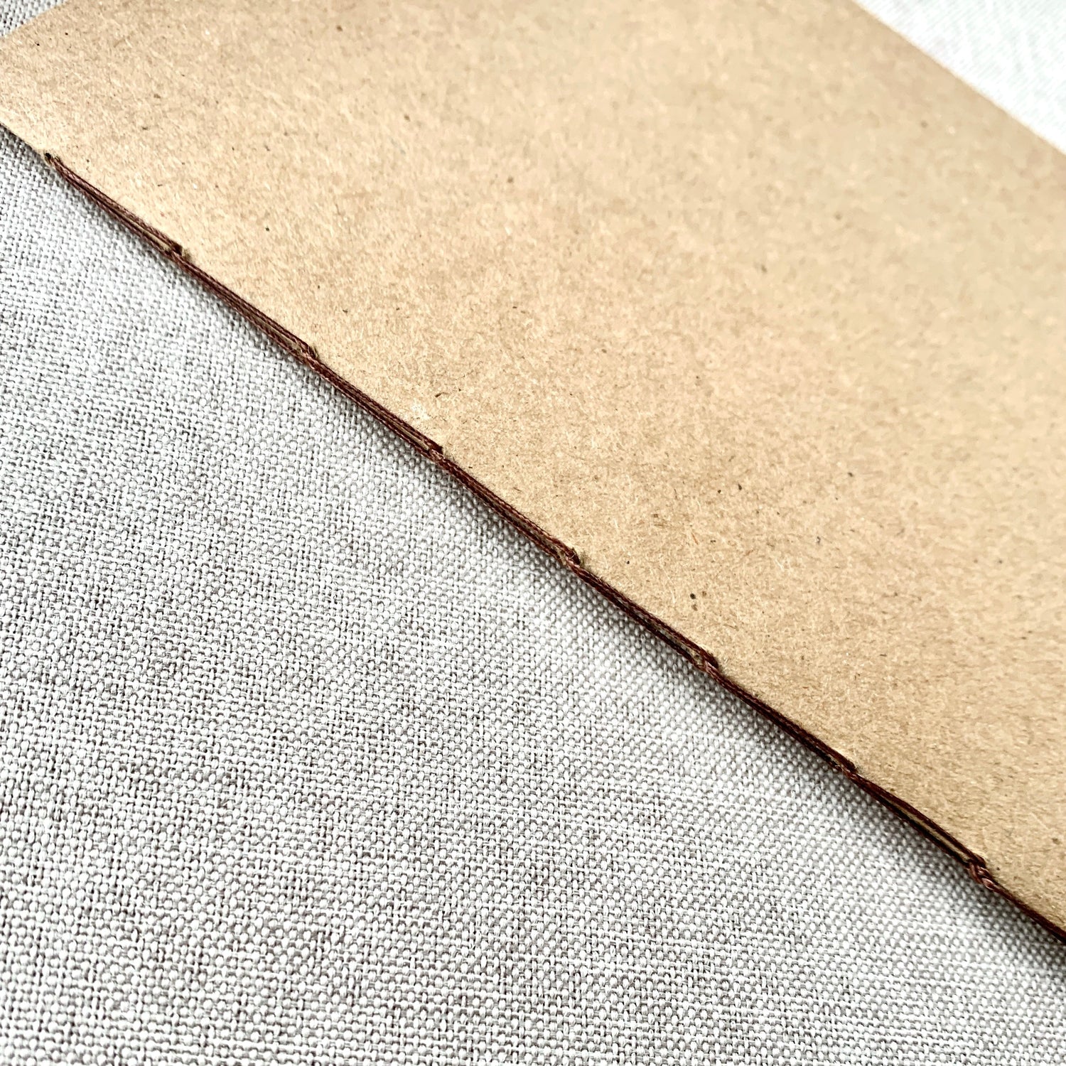 Close-up of the hand-stitched binding on an A5 Blank Travelers Notebook Insert – Fountain Pen Friendly, Hand-Stitched Kraft Cover, showcasing the durable kraft cover texture.