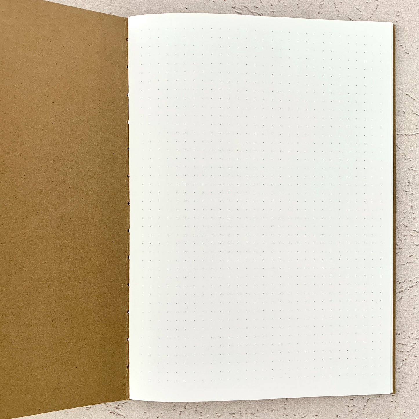 Open A5 Dot Grid Travelers Notebook Insert showing light grey dot grid pattern on white pages with hand-stitched kraft cover, designed to be fountain pen friendly and ideal for bullet journaling or planning.