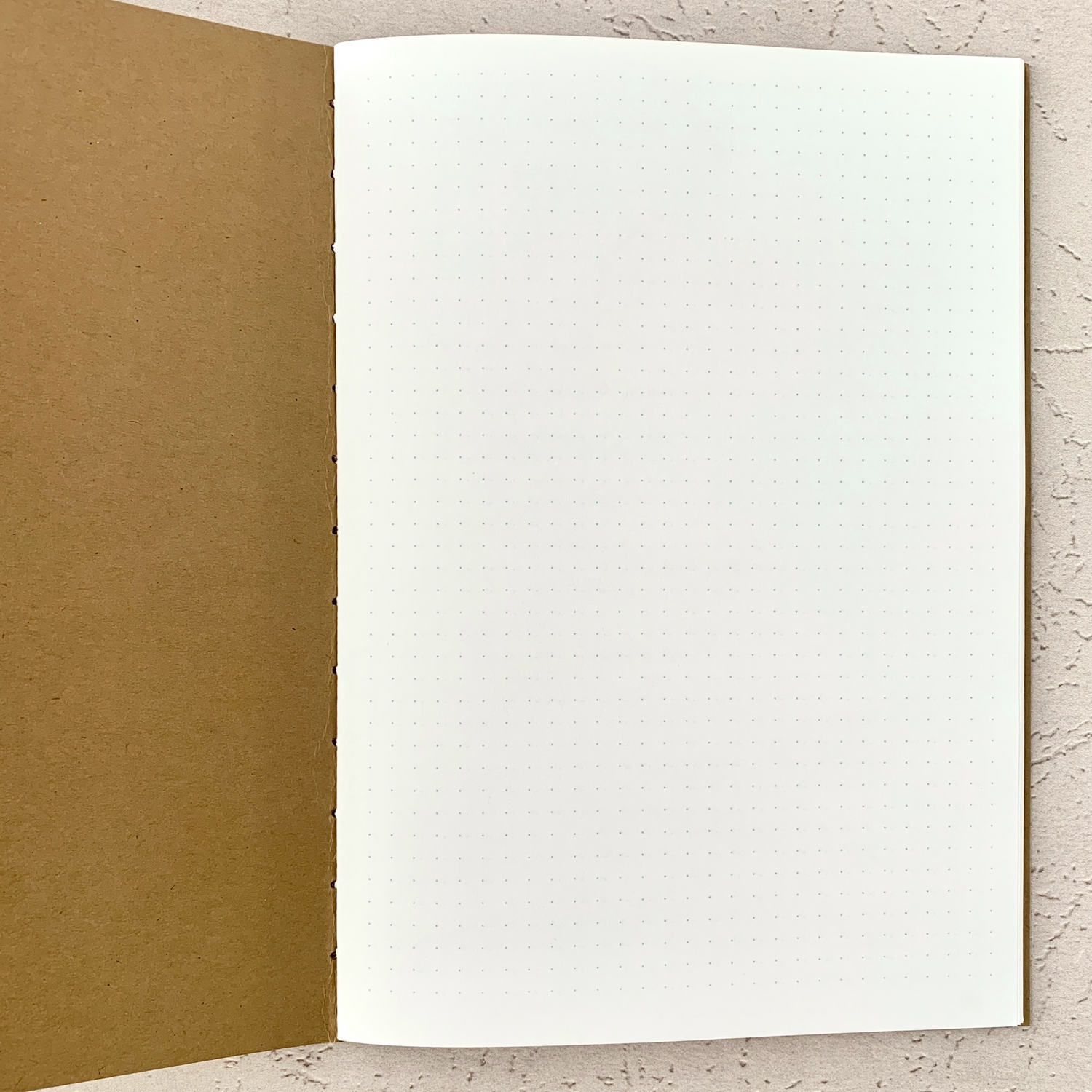 Open A5 Dot Grid Travelers Notebook Insert showing light grey dot grid pattern on white pages with hand-stitched kraft cover, designed to be fountain pen friendly and ideal for bullet journaling or planning.
