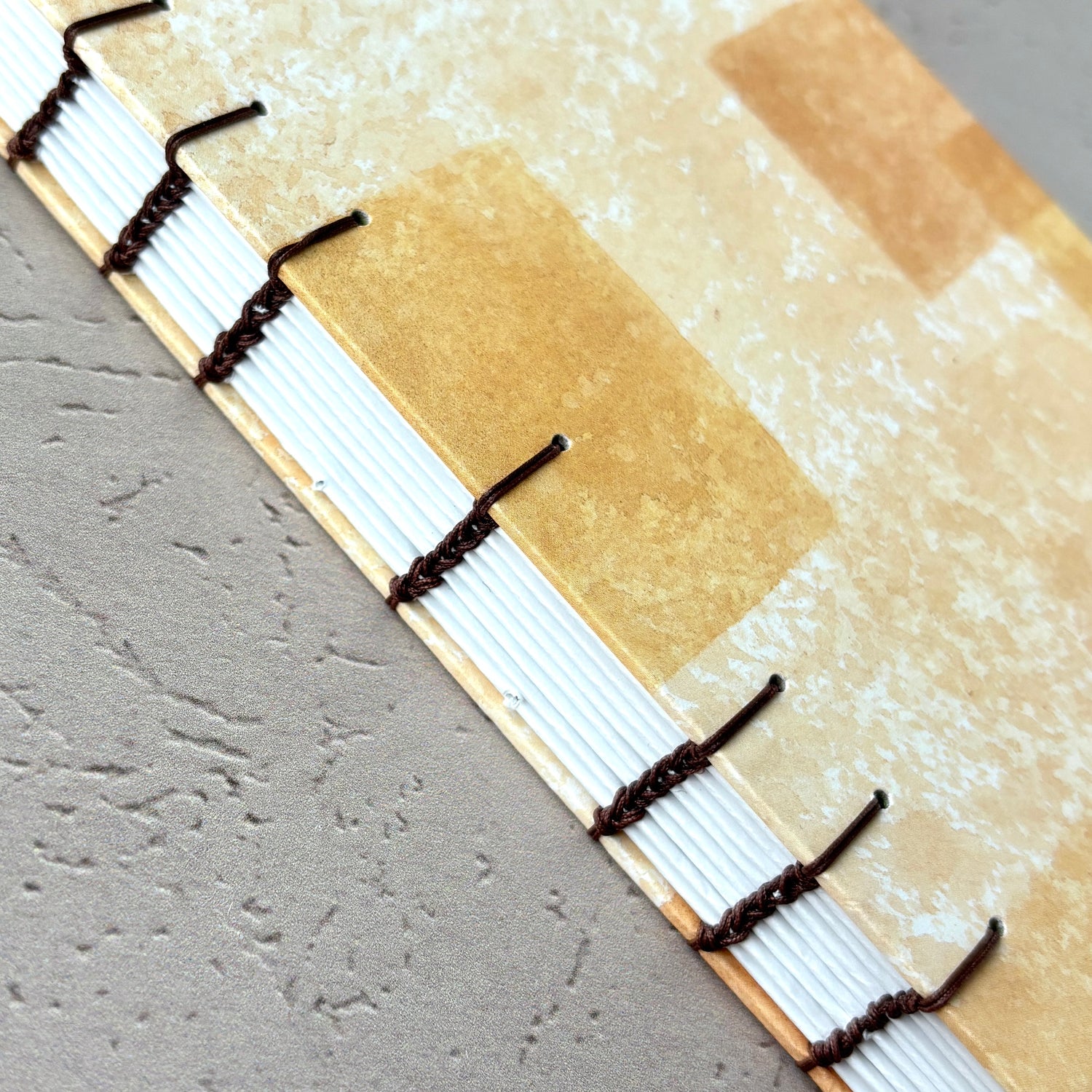 Blocked Orange - A6 - Lined - Coptic Bound - Fountain Pen Notebook - Handmade Journal showing exposed stitched binding and textured orange cover
