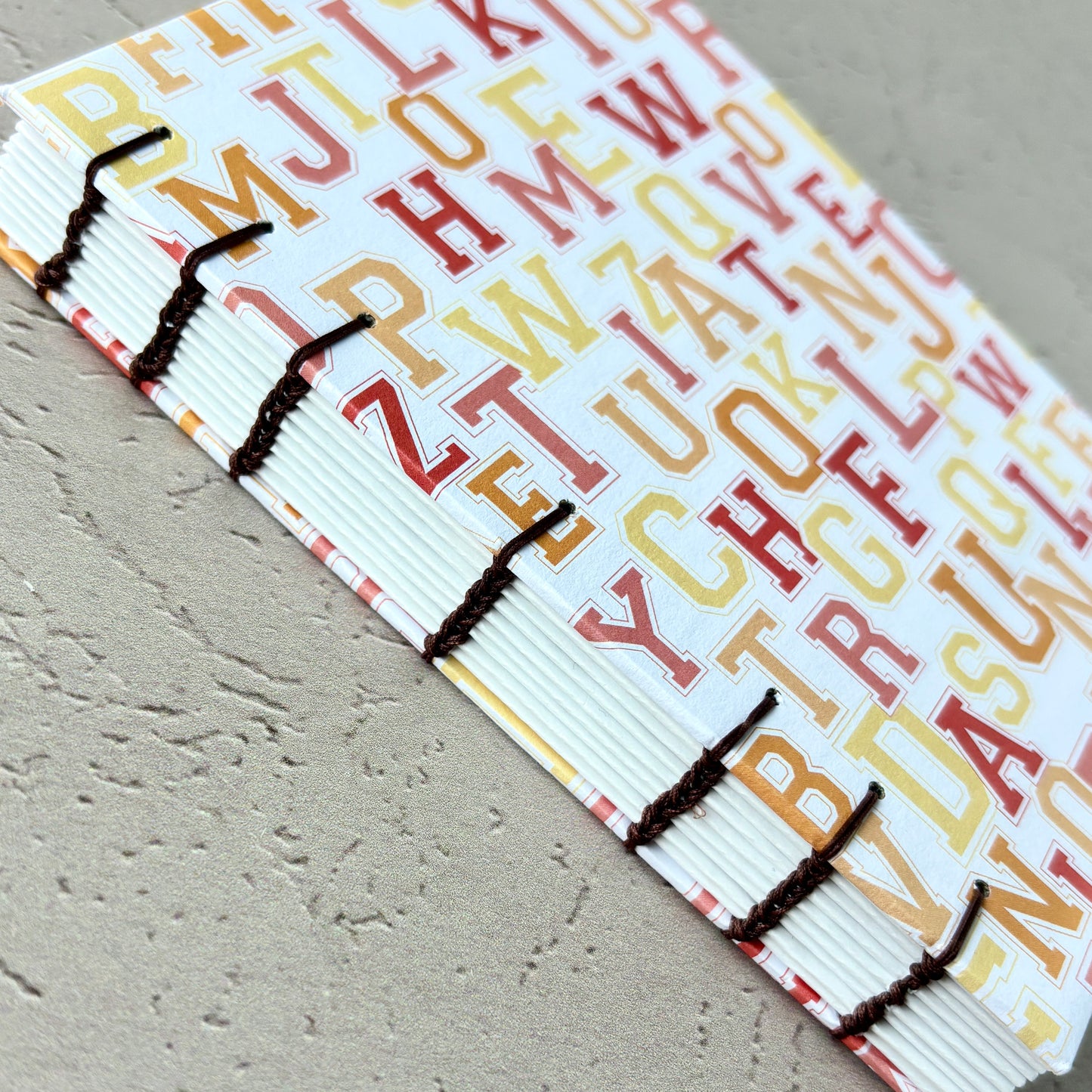 University Monogram - A6 - Lined - Coptic Bound - Fountain Pen Notebook - Handmade Journal with colorful alphabet cover and visible black coptic stitching