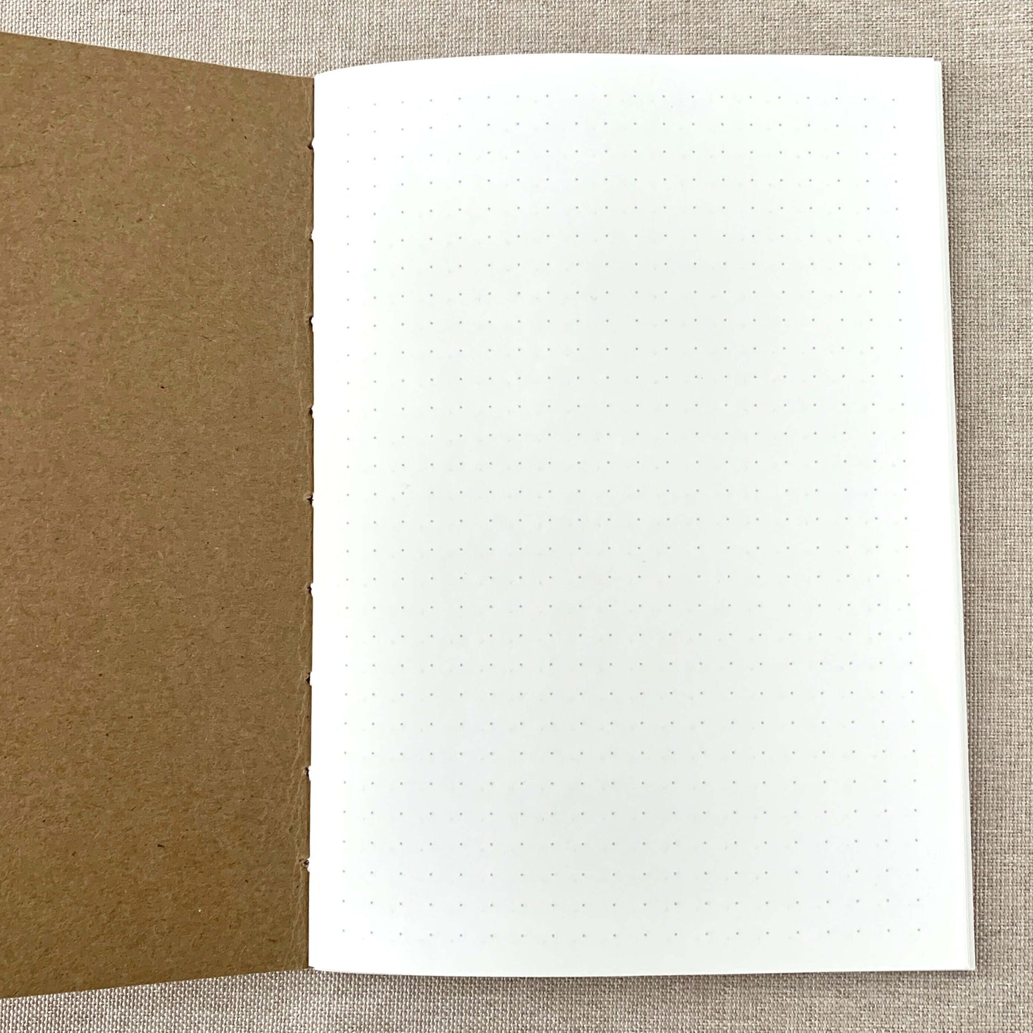 Open A6 Dot Grid Travelers Notebook Insert - Fountain Pen Friendly, Hand-Stitched Kraft Cover showing white dot grid paper and brown kraft cover, ideal for bullet journaling and fountain pen use.